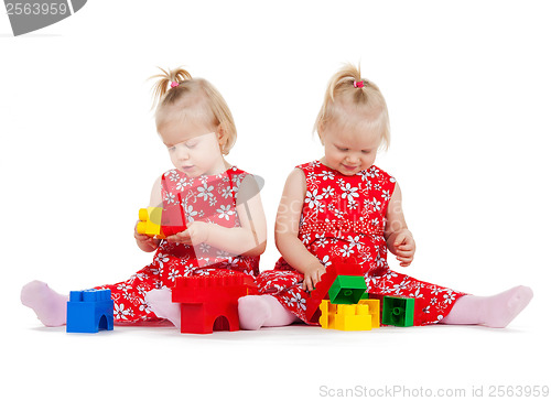 Image of two twin girls in red dresses playing with blocks