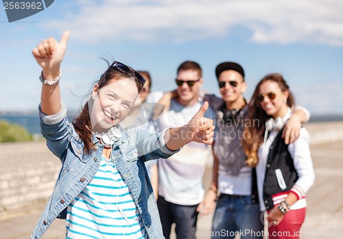 Image of teenage girl with headphones and friends outside