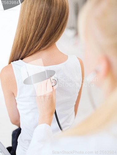 Image of doctor with stethoscope listening to child back