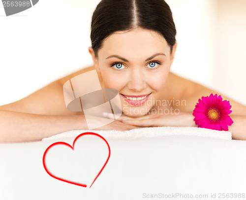 Image of smiling woman with flower in spa salon