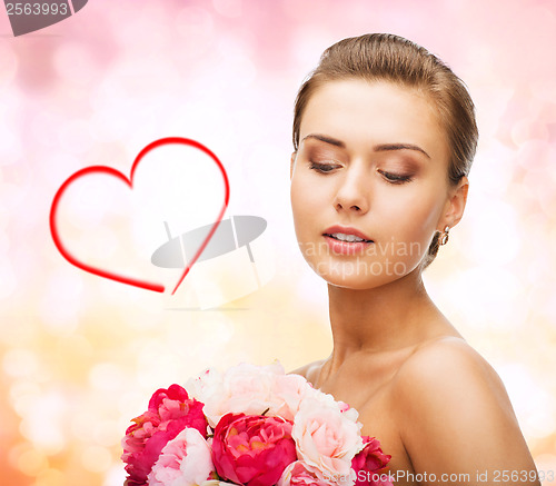Image of woman wearing earrings and holding flowers