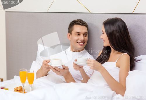 Image of smiling couple having breakfast in bed in hotel