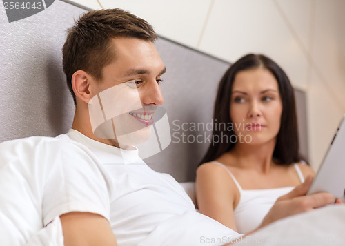 Image of smiling couple in bed with tablet pc computers