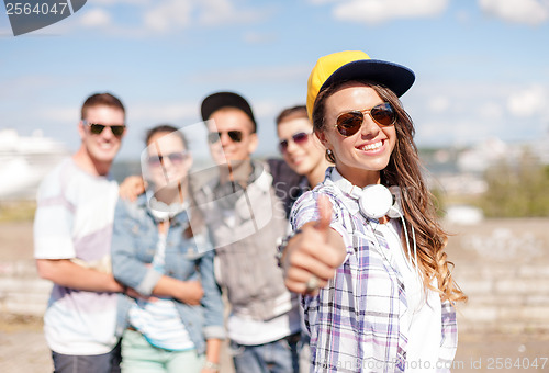 Image of teenage girl with headphones and friends outside