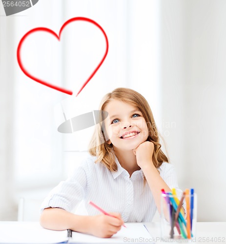 Image of smiling little student girl drawing at school