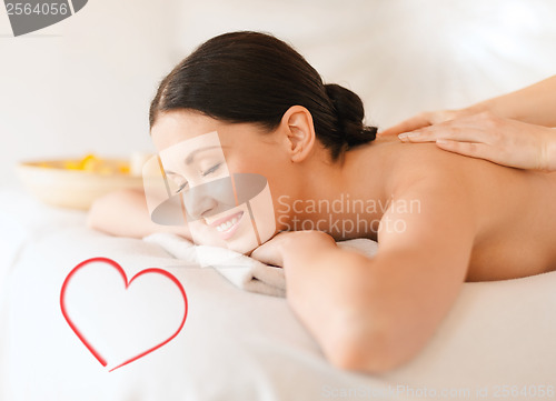 Image of smiling woman in spa salon getting massage