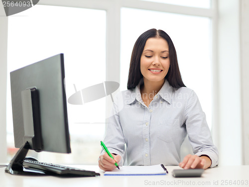 Image of woman with computer, notebook and calculator