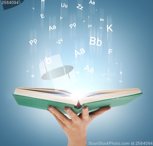 Image of hand holding open book with magic lights