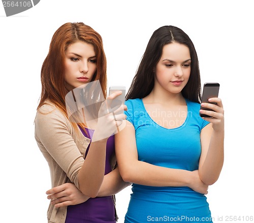 Image of two serious teenagers with smartphones