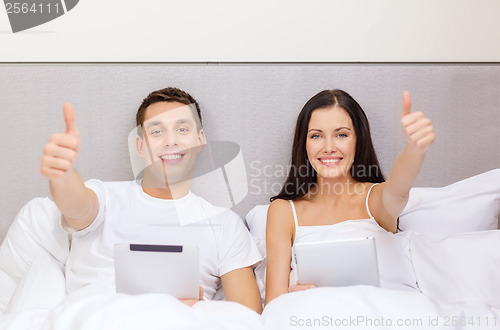 Image of smiling couple in bed with tablet pc computers