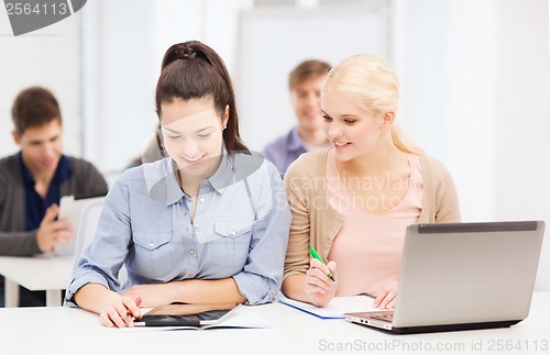 Image of two smiling students with laptop and tablet pc