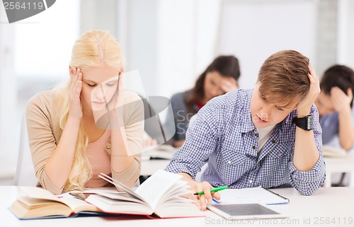 Image of tired students with tablet pc, notebooks and books