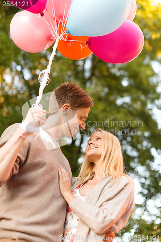 Image of smiling couple with colorful balloons in park