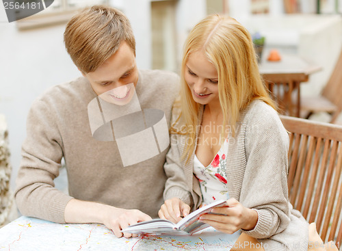 Image of couple with map, camera and city guide in cafe