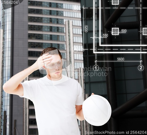 Image of male architect in safety glasses taking off helmet