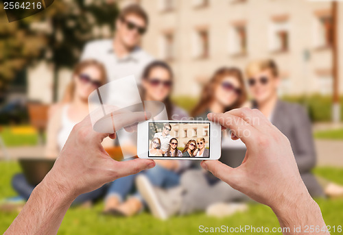 Image of close up of hands making picture of group of teens