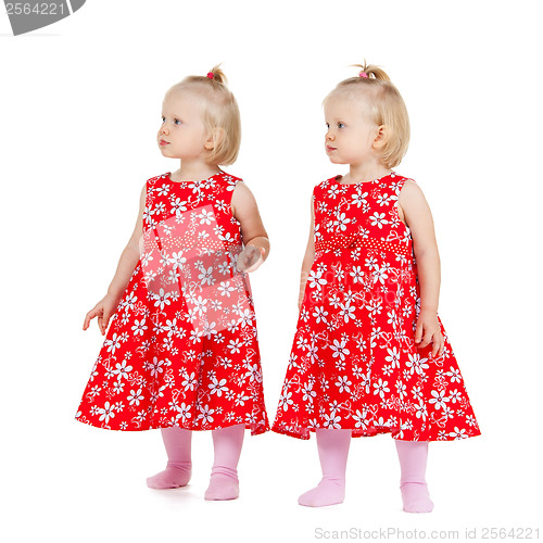 Image of two identical twin girls in red dresses looking