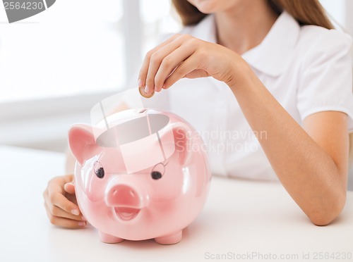 Image of smiling child putting coin into big piggy bank