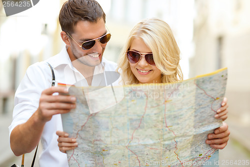 Image of smiling couple in sunglasses with map in the city