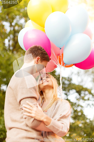 Image of smiling couple with colorful balloons in park