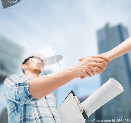 Image of builder with blueprint shaking partner hand