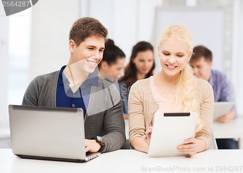 Image of two smiling students with laptop and tablet pc
