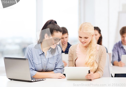 Image of two smiling students with laptop and tablet pc