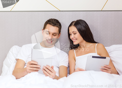 Image of smiling couple in bed with tablet pc computers