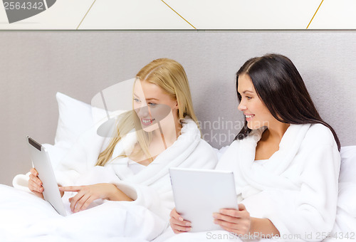 Image of girlfriends with tablet pc computers in bed