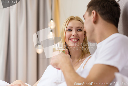 Image of smiling couple with champagne glasses in bed