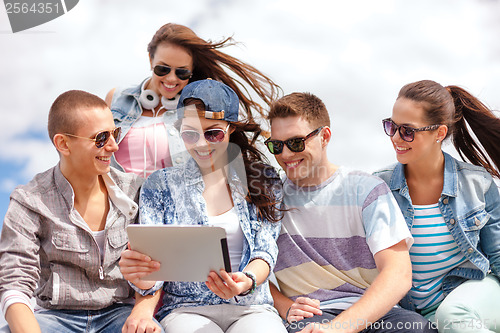 Image of group of smiling teenagers looking at tablet pc