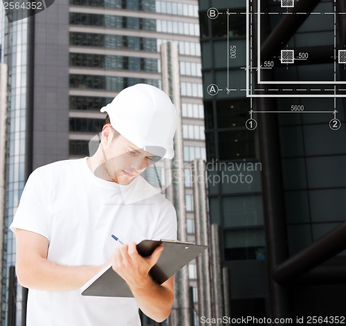 Image of male architect in helmet looking at blueprint