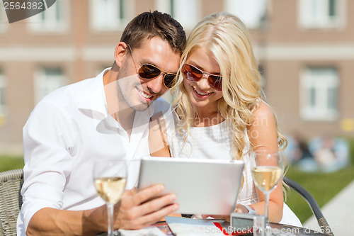 Image of couple looking at tablet pc in cafe