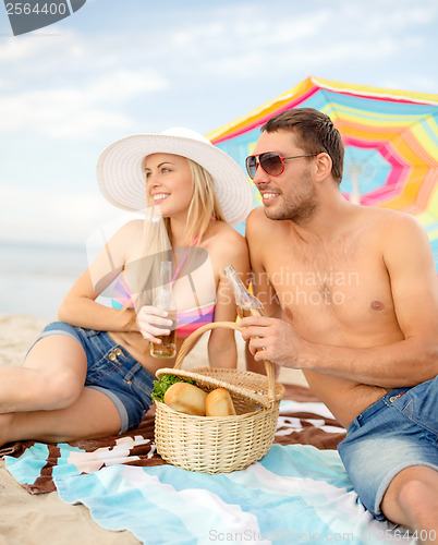 Image of smiling couple having picnic on the beach