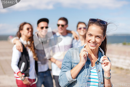 Image of teenage girl with headphones and friends outside