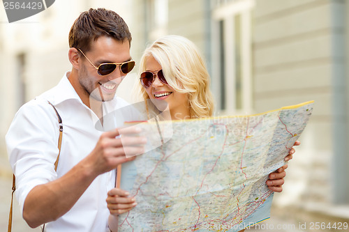 Image of smiling couple in sunglasses with map in the city