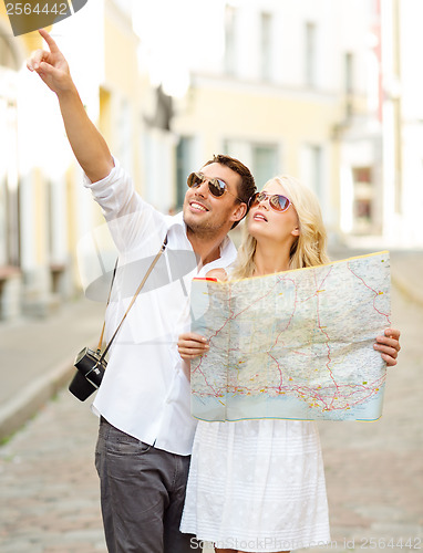 Image of smiling couple in sunglasses with map in the city