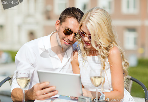Image of couple looking at tablet pc in cafe