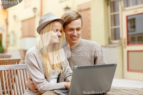 Image of smiling couple with laptop computer in cafe