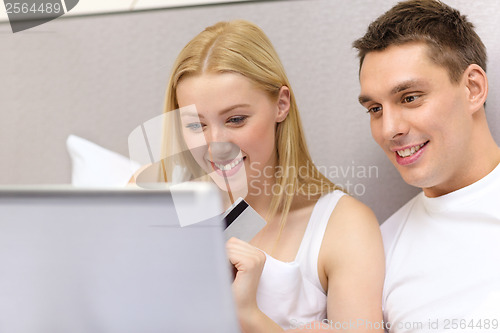 Image of couple in bed with laptop computer and credit card