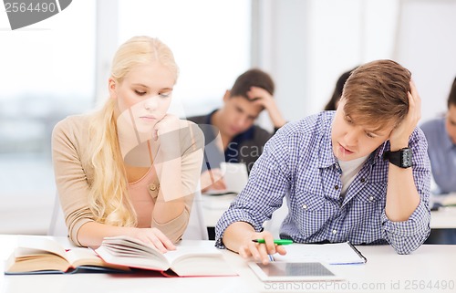 Image of tired students with tablet pc, books and notebooks