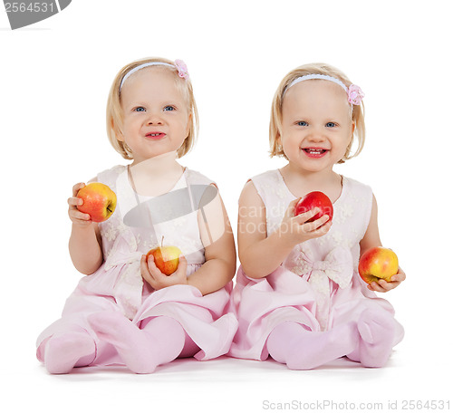 Image of two identical twin girls playing with apples