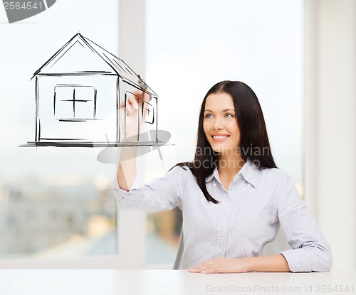 Image of smiling woman drawing house on virtual screen