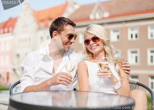 Image of smiling couple in sunglasses drinking wine in cafe