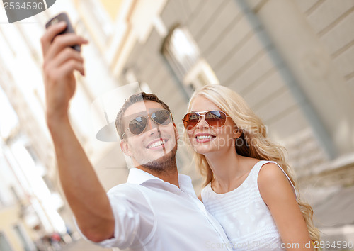 Image of smiling couple with smartphone in the city