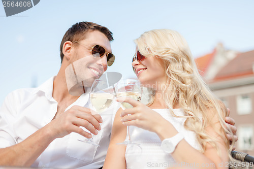 Image of smiling couple in sunglasses drinking wine in cafe