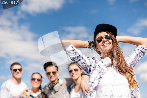Image of teenage girl with headphones and friends outside