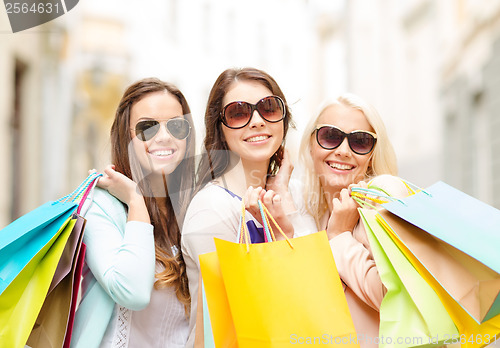 Image of three smiling girls with shopping bags in city