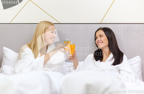 Image of smiling girlfriends having breakfast in bed