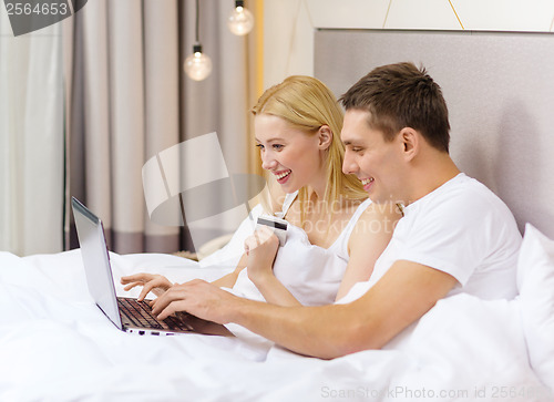 Image of couple in bed with laptop computer and credit card